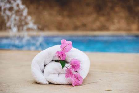White towel with pink flowers near the spa pool in the hotel on vacationの写真素材
