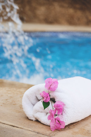 White towel with pink flowers near the spa pool in the hotel on vacationの写真素材