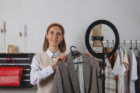 Woman millennial fashion stylist records fashion video on smartphone with ring lampの写真素材