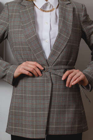 Woman tightens belt on classic plaid blazer for office workの写真素材