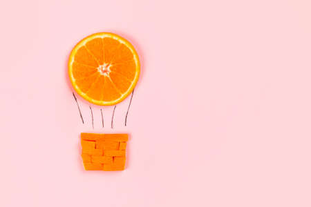 Flying hot air balloon from orange. Creative layout. Summer travel and entertainment concept.の写真素材