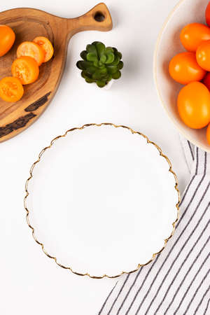 Dinner plate mockup. White plate in the kitchen with tomatoes on a white table. Flat lay mock upの写真素材