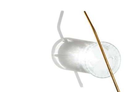 Transparent glass of water with reusable metal eco straw in sunlight with shadows.の写真素材