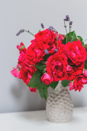Garden roses in a gray vase in a minimalistic interior. Spring rustic background with delicate...