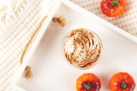 Pumpkin latte with whipped cream and syrup on a white tray with a plaid and small autumn Halloween pumpkins.の写真素材