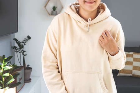 Woman wearing beige sweatshirt hoodie Mock up. Mothers day mockup in light home interiorの写真素材