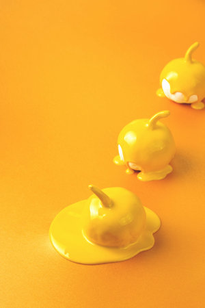 Three yellow Halloween pumpkins with liquid paint flowing. Minimal Holiday season concept orange background.の写真素材