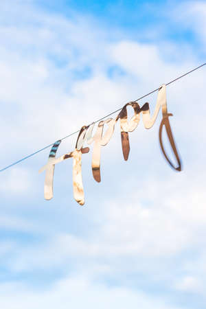 Golden word happiness hangs on garland against background of blue sky with clouds. Concept of celebration of life, happiness and mental health.の写真素材