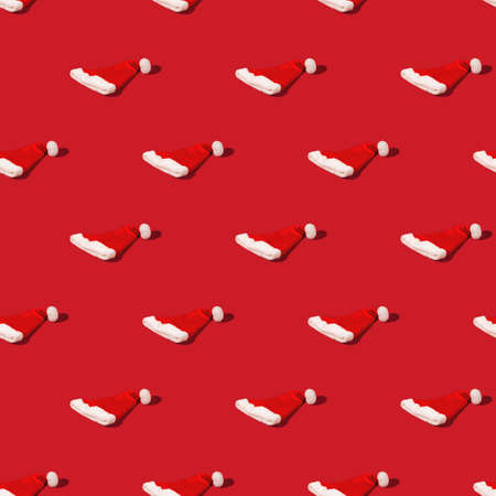 Seamless pattern with Red Santa Claus hat on monohomic background. Minimalistic Christmas composition.の写真素材
