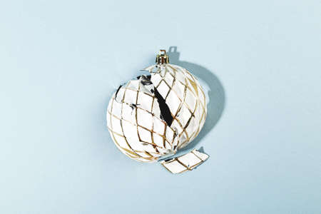 White Christmas ball with shattered or broken shell on blue background. Minimalistic creative trendy Christmas composition.の写真素材