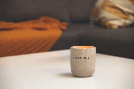 Concrete candlestick on table in living room next to sofa with pillows and blanket. Autumn comfort hyggelig at homeの写真素材