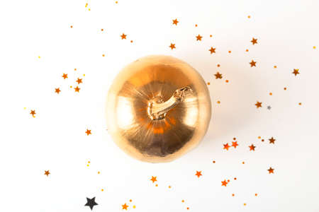 Golden decorative Halloween pumpkin on a light background among gold stars.の写真素材