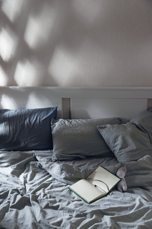 Open diary to write on the bed with blue textiles in the moonlight. Evening rituals for mental health.の写真素材