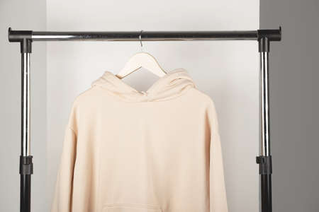 Blank beige unisex sweatshirt mockup on clothes hanger. Hoodie mock up in minimal interior.の写真素材