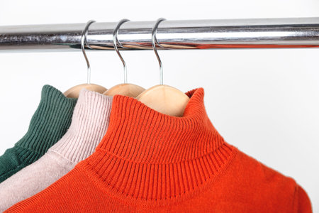 Basic autumn womens wardrobe concept. Blank turtleneck sweaters on clothes hanger. Bright orange...