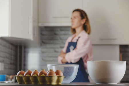 Packing eggs and bowls for making dough on background of kitchen and woman who cooks at home.の写真素材