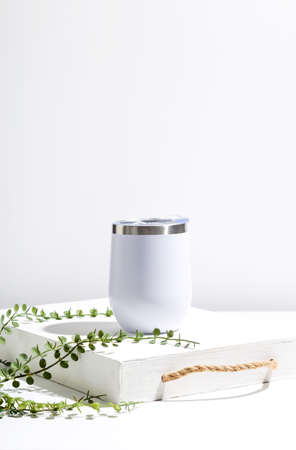 White thermo cup mock up with green plant on wooden tray. Minimal composition to present design.の写真素材
