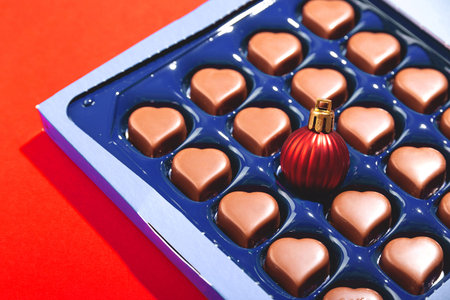 Creative Christmas concept with Christmas ball in box of heart shaped chocolates.の写真素材