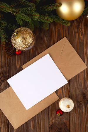 Christmas card mockup. White minimal empty postcard on wooden table with festive decorations and craft letters.の写真素材