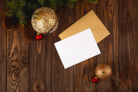 Christmas card mockup. White minimal empty postcard on wooden table with festive decorations and...