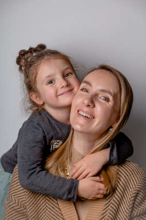 Portrait of happy and beautiful mother with her daughter on minimal gray background.の写真素材