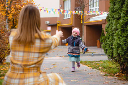 Mother playing with daughter on autumn street. Fall colorsの写真素材