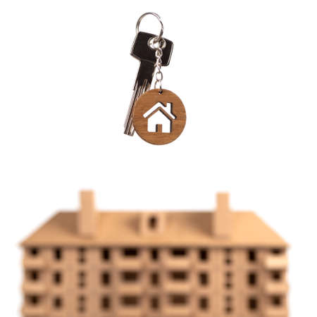 Real estate concept. Keys with house shaped keychain against brown house model.の写真素材