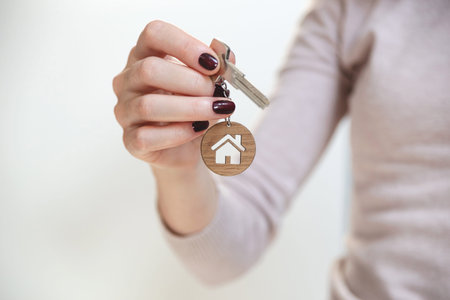 Real estate concept. Keys with a house shaped keychain in a womans hand.