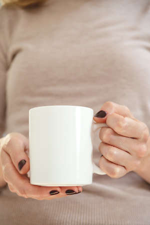 White coffee mug mockup for design demonstration. Stylish cup mock up in female hand.の写真素材
