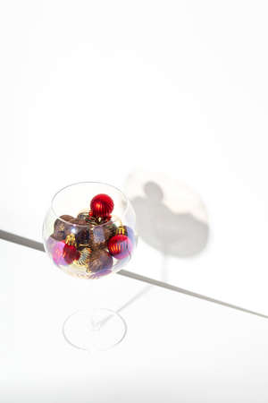 Christmas creative image with red and gold Christmas balls in glass. In hand on blue background.の写真素材