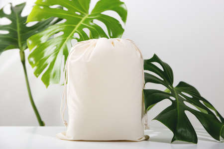 Reusable Eco bag mock up for zero waste shopping among green leaves of monstera. Minimal trendy composition.の写真素材