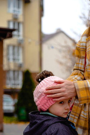 Mom straightens her daughters hat and hair during an autumn walk. Fall colorsの写真素材