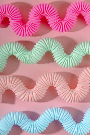 Curved pink blue mint antistress pop tube toy with shadow on pink background. Bright kid toy. Wallpaperの写真素材