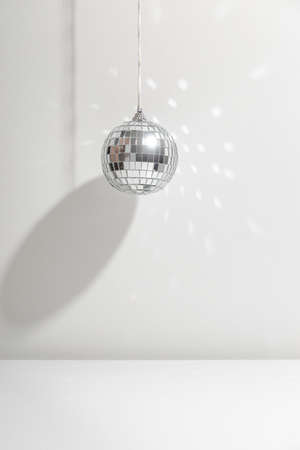 Silver disco ball reflects sunlight on silver background with shadow. Copyspace.の写真素材