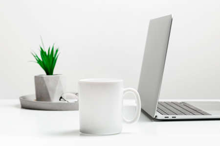 White mug mockup on modern stylish workplace with laptop. Cup mockup.の写真素材