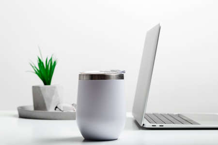 White thermo cup mock up on modern stylish workplace with laptop. Cup mockup.の写真素材