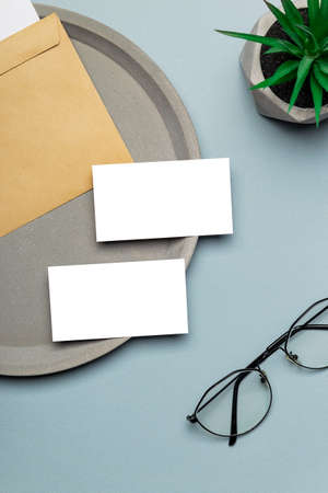Two business cards mockups on modern minimal workplace with eyeglasses. Top view desktop.の写真素材
