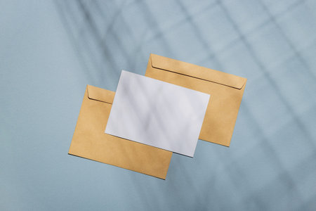 Postcard mockup on blue background with craft envelopes in shadows. Card mock up.