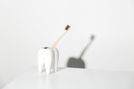 Eco-friendly bamboo toothbrush in a tooth-shaped stand. Conscious consumption and dental care...