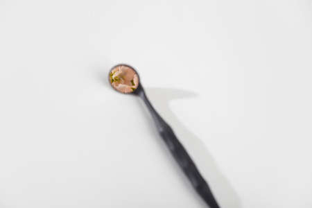Dentist mirror with flowers reflection on white background. Minimalism. Dental care concept. Copy space.の写真素材