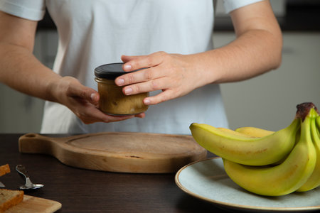 Peanut butter in woman hands in the kitchen.の写真素材