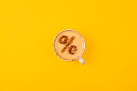 Percentage sign on a cup of coffee. Discount concept. Yellow background.