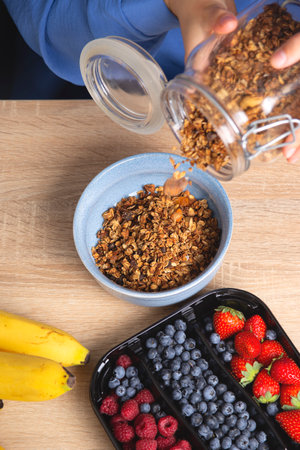 Granola in glass jar. Woman prepares quick breakfast.の写真素材