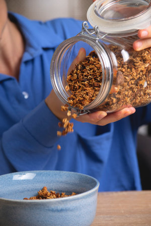 Granola in glass jar. Woman prepares quick breakfast.の写真素材