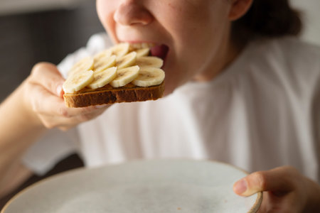 Eating sandwich with peanut butter and banana. American breakfast concept.の写真素材