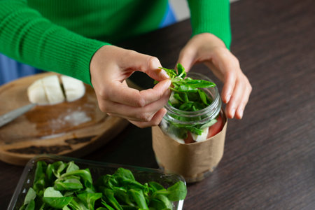 Woman making vegan salad in jar with chickpea. Cooking healthy food.の写真素材