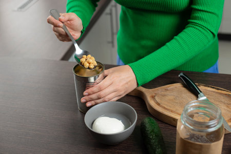 Woman opens can of chickpeas to make salad.の写真素材