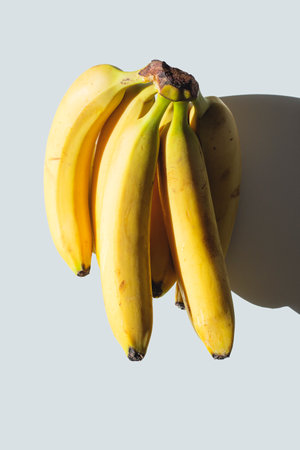 A bunch of bananas on a white table in sunlight.の写真素材