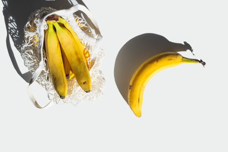 Ripe organic bananas on white table in sunlight.の写真素材