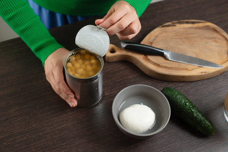 Woman opens can of chickpeas to make salad.の写真素材
